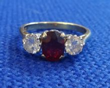 A 18ct three stone engagement ring set with an oval faceted cut ruby and two brilliant cut diamonds,