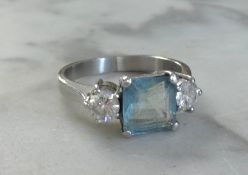 A platinum three stone ring set with a rectangular aqua marine and two brilliant cut diamonds, the