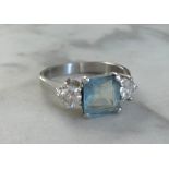 A platinum three stone ring set with a rectangular aqua marine and two brilliant cut diamonds, the