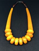 A yellow amber style necklet and a red amber style graduated bead bracelet (2).