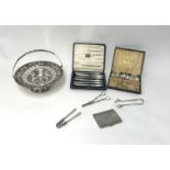 A silver plated cake basket, cigarette case, grape scissors, tongs also a cased set of six silver