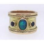 A 9ct gold thumb ring set with two ceylon sapphires and an opal, commissioned and produced by Crazy