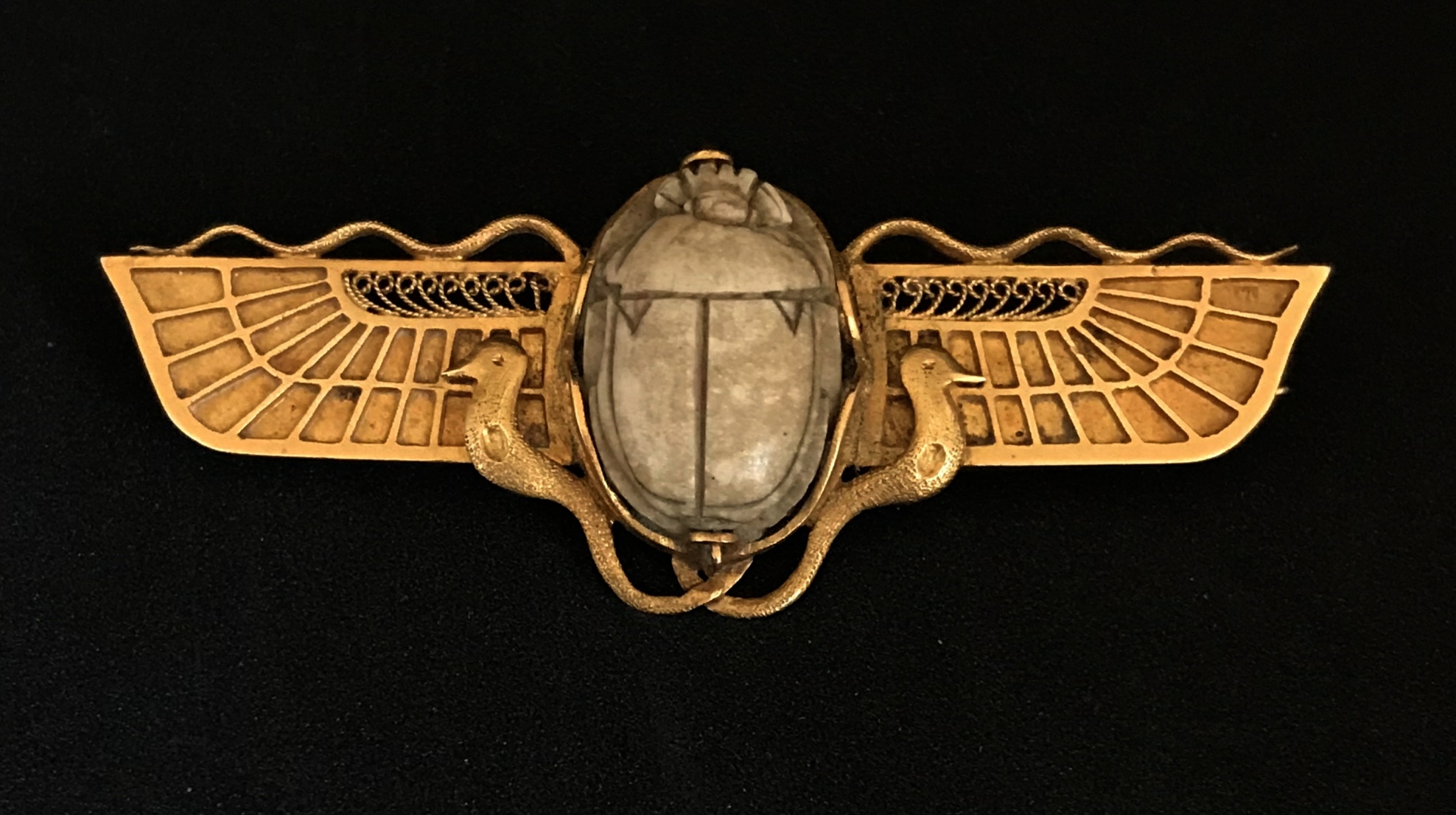 An antique gold Egyptian Revival brooch set with a carved hardstone scarab indistinctly marked,