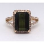 A 14k tourmaline ring set, the emerald cut green tourmaline approx 3.30ct, within a border of