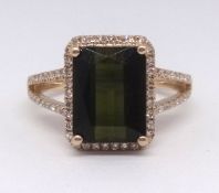 A 14k tourmaline ring set, the emerald cut green tourmaline approx 3.30ct, within a border of