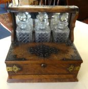 A 19th Century walnut three bottle Tantalus, the cabinet with Bramah lock, fitted with a drawer