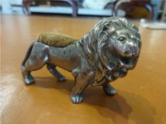 A silver plated lion pin cushion and a silver watch case (2)