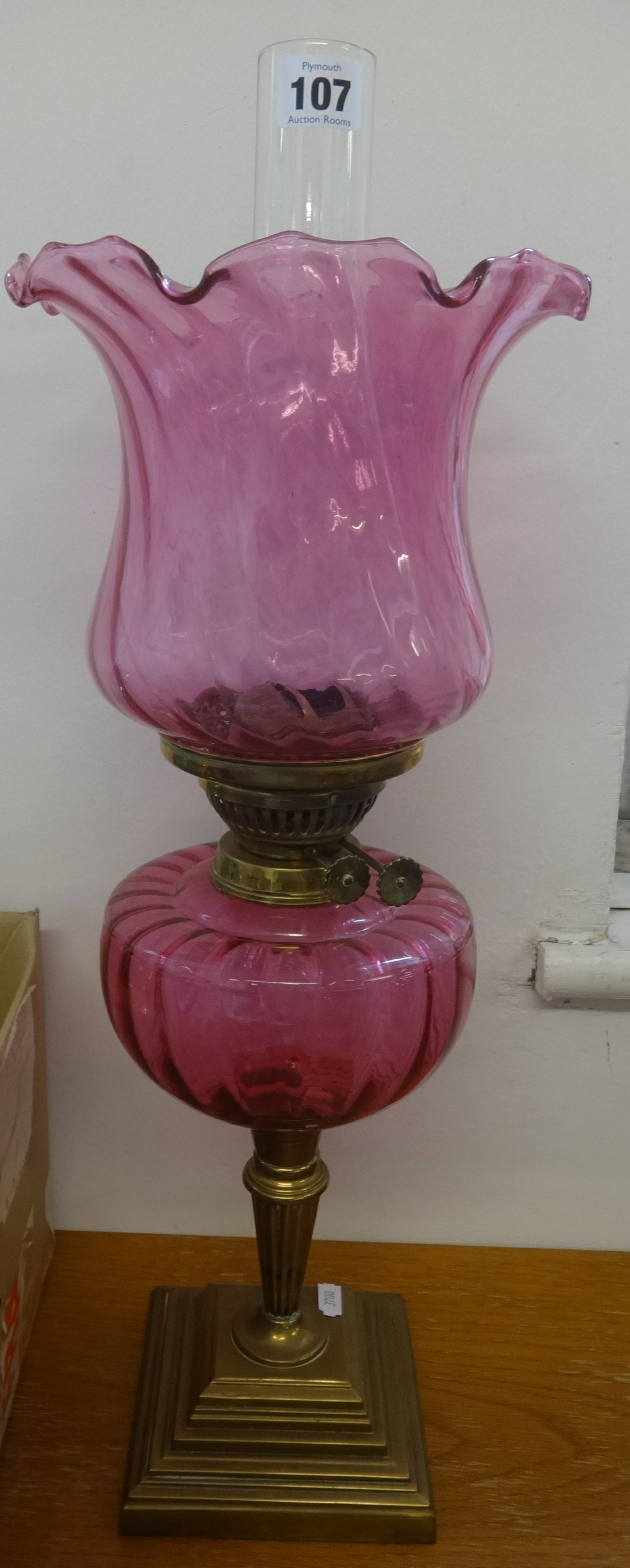 A oil lamp with cranberry glass reservoir and shade on brass stepped base, overall height to top