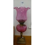 A oil lamp with cranberry glass reservoir and shade on brass stepped base, overall height to top