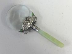 An oriental jade style magnifying glass with ornate white metal mount.