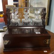 A 20th Century three bottled Tantalus with a mahogany case, key and a storage box containing three