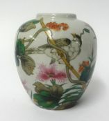 An oriental porcelain jar decorated with bright flowers and a bird, height 14cm.