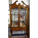 Edwardian mahogany two door display cabinet, with swan neck pediment, fitted with two drawers on