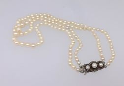 A double string of cultured pearls with silver and pearl clasp.