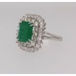 An emerald and diamond rectangular cluster ring, comprising central octagon cut emerald surrounded