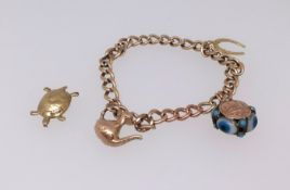A yellow gold bracelet with curb links, three charms, approx 25.6gms