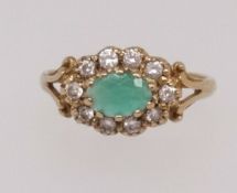 A 9ct emerald and diamond cluster ring, finger size K1/2.