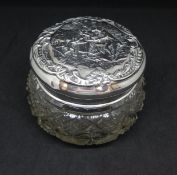 A silver top jar the lid with embossed decoration of figures within a scroll work border.