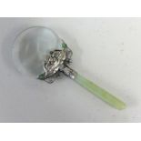An oriental jade style magnifying glass with ornate white metal mount.