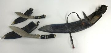 Three Kukri knives including an unusual large model with a carved wood handle.