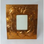 A Newlyn copper picture frame embossed with fish and a shell, impressed 'Newlyn' to verso, 30cm x