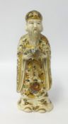 A Chinese porcelain figure of a man with long beard, gilt decorated cloak and hat