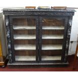 A late Victorian heavily carved dark oak free standing and glazed bookcase, width 120cm