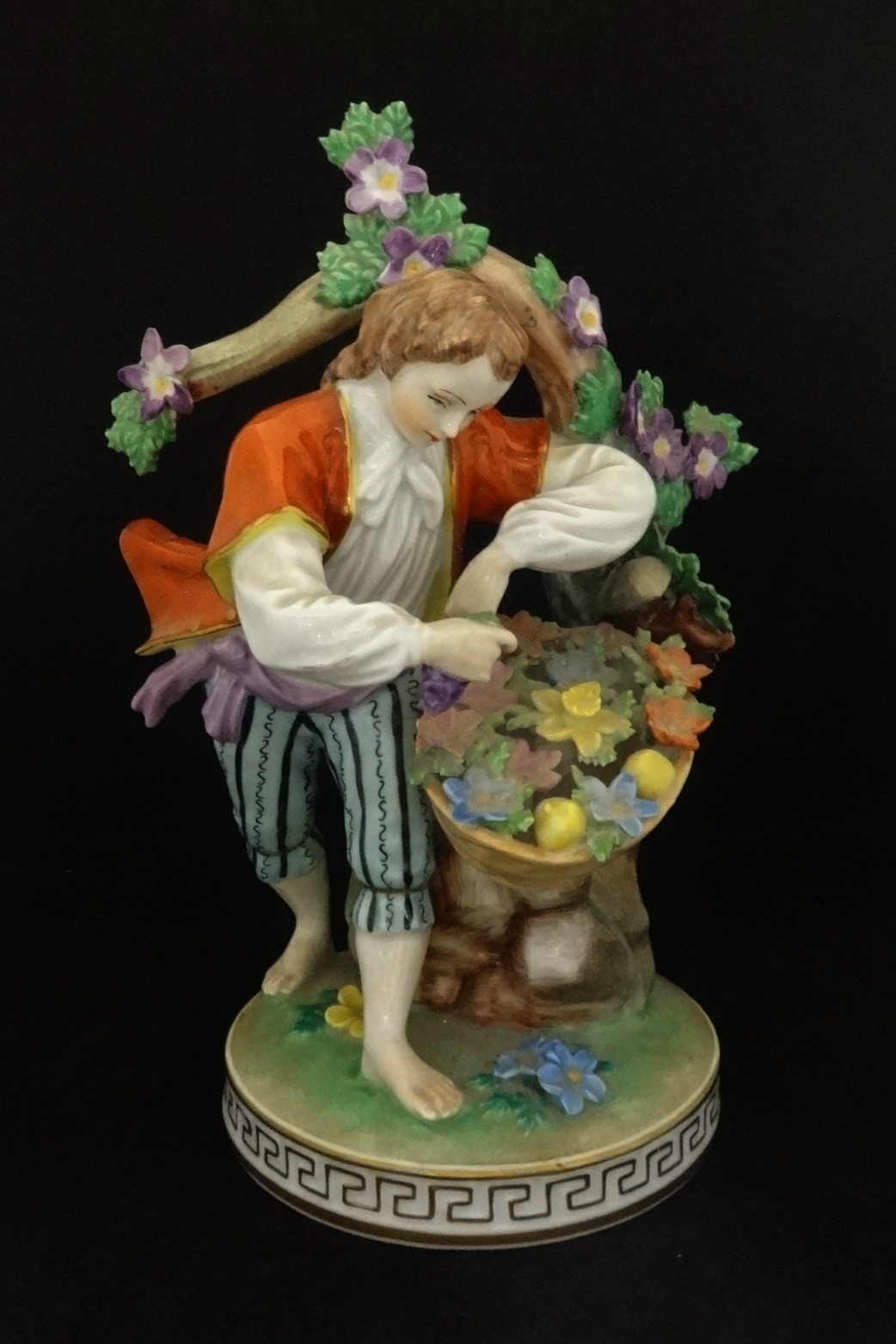 Dresden, an early 20th century porcelain figure in period costume before a tree picking wild