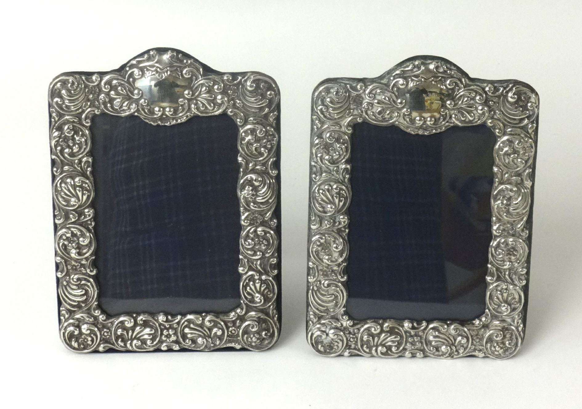 A pair of silver photo frames with embossed scroll work decoration glazed, approx. 21cm x 15cm