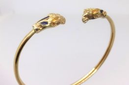 An 18ct gold yellow metal rams head bangle set with blue stone, approx. 11.5gms.
