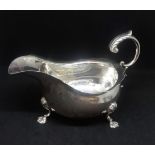 George V silver sauce boat with scallop edge and paw feet with acanthus scroll handle, Walker & Hall