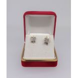 A pair of princess cut diamond stud earrings each of square form set with nine stones in yellow