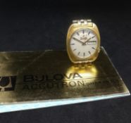A gents Bulova Accutron Date, series 218 gilt wristwatch and booklet.