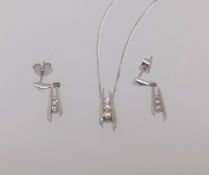 A modern 9ct white gold and diamond contemporary pendant and matching earrings.