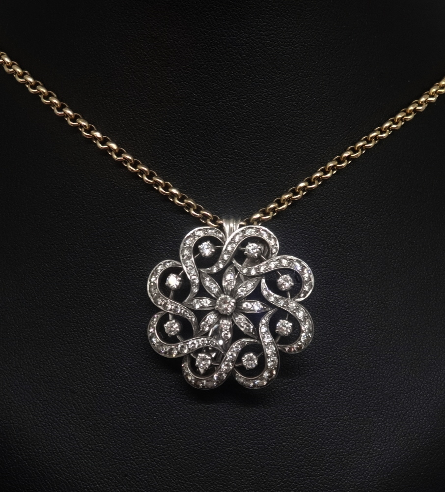 A diamond set swirl combination pendant brooch set in white metal and a 9ct yellow gold chain and
