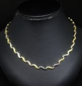 An 18ct necklet set with alternate yellow and white gold fancy wave design, links stamped 750, 28.