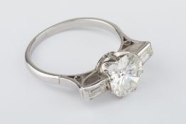 A fine diamond ring set with a single round cut diamond and a pair of baguette cut diamonds on the