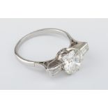 A fine diamond ring set with a single round cut diamond and a pair of baguette cut diamonds on the