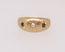 An 18ct gypsy style three stone sapphire and diamond ring, finger size F.