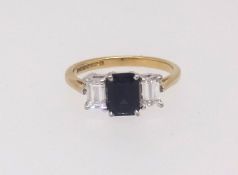 An 18ct sapphire and diamond three stone ring the centre stone rectangular flanked by a pair of