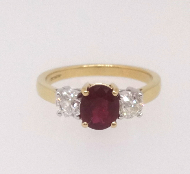 An 18ct ruby and diamond three stone ring, finger size M.