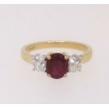 An 18ct ruby and diamond three stone ring, finger size M.