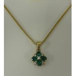 A emerald and diamond cluster pendant necklace set in yellow gold.