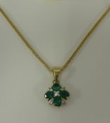 A emerald and diamond cluster pendant necklace set in yellow gold.