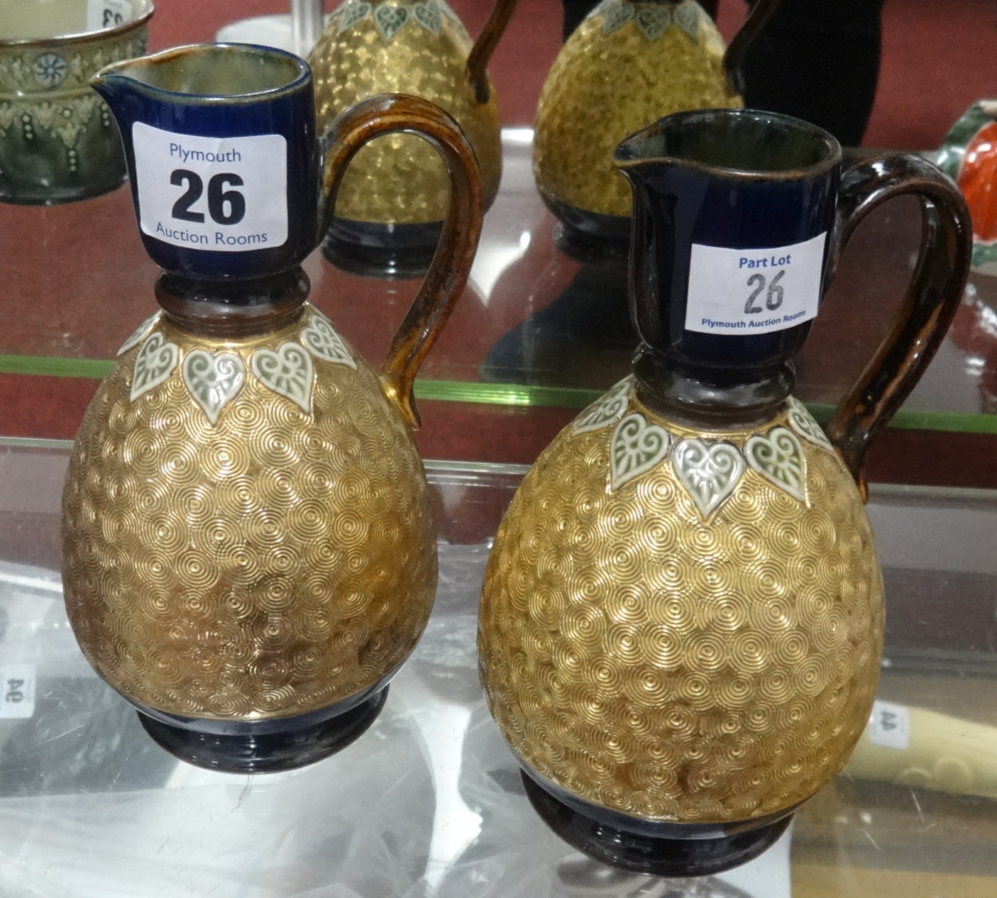 Royal Doulton, a pair of jugs with gilded swirl decoration, height 16cm.
