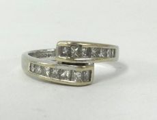 An 18ct white gold and diamond channel set cross over ring, finger size M.