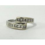 An 18ct white gold and diamond channel set cross over ring, finger size M.
