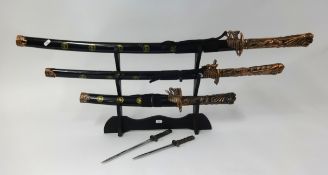 Replica trio of samurai swords on stand.