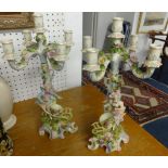 A pair of 19th Century porcelain candelabra, decorated with flowers and figures each in two parts,