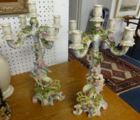 A pair of 19th Century porcelain candelabra, decorated with flowers and figures each in two parts,
